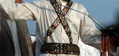 A badu with bandoliers sheathing his sword