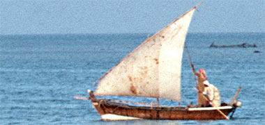 A small craft being poled with a lateen sail and simple painted prow