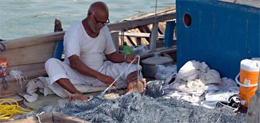 A crew man carrying out repairs on his nets