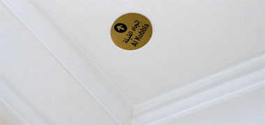 A sign on a hotel ceiling indicating the direction of prayer