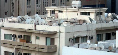 Water tanks and television dishes on top of a building
