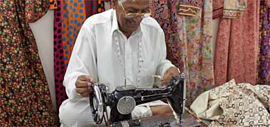 A male tailor sewing a dress in the suq