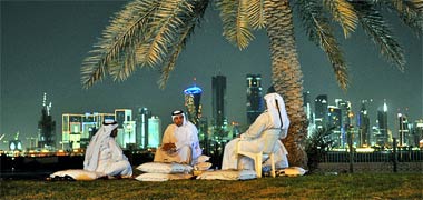 Three men sit talking on the Corniche
