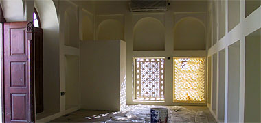 A view of the end of a room with perforated naqsh panels