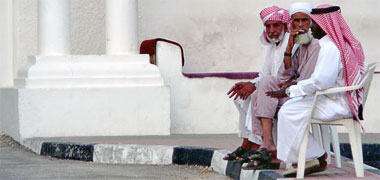 Three men sitting outside one of the old palaces in Doha