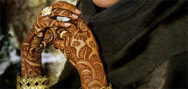The hands of a young woman with jewelled rings and dyed with henna
