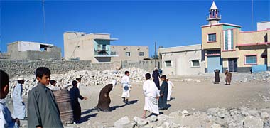 Children playing football on a cleared area of land