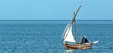 A small craft underway with a lateen sail and simple painted prow
