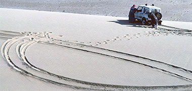 A car being pushed off a sand dune