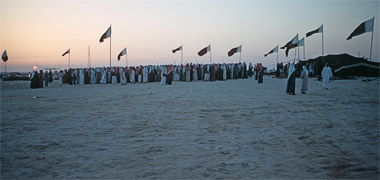 National flags flying at dusk at a razeef
